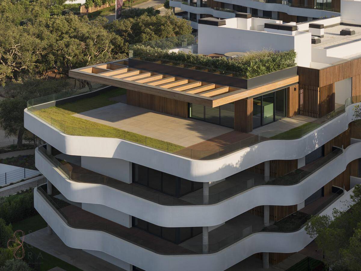 Luftaufnahme eines modernen Apartmentgebäudes mit begrünten Dächern und Holzverkleidung.