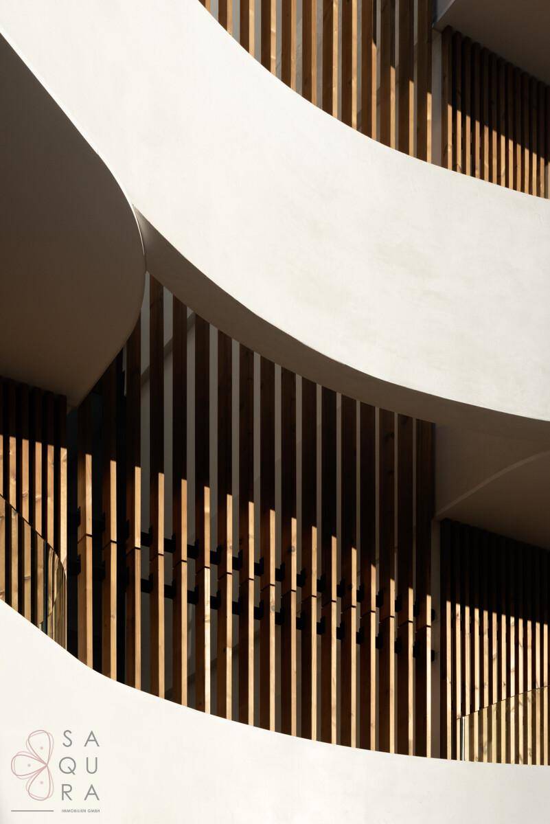 Abstrakte Detailansicht der geschwungenen Balkone und vertikalen Holzlamellen der modernen Fassade.