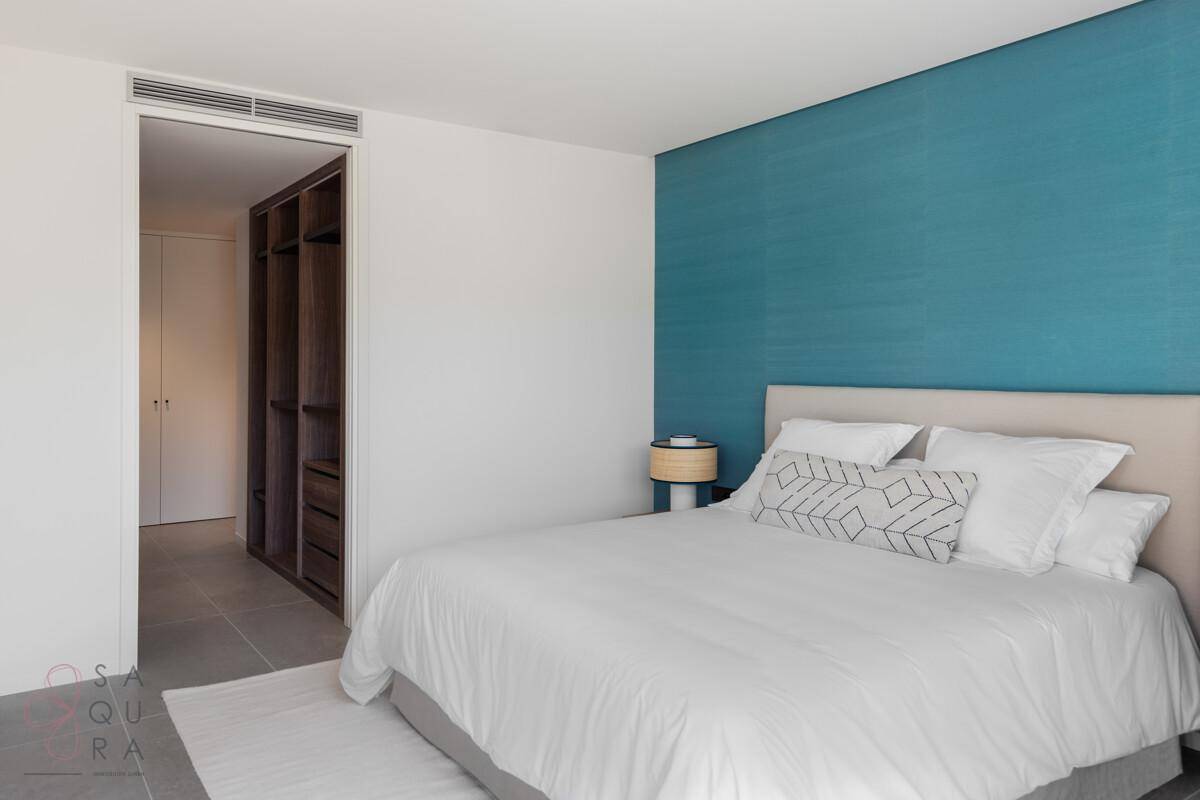 Helles Schlafzimmer mit blauer Akzentwand und integriertem begehbarem Kleiderschrank.