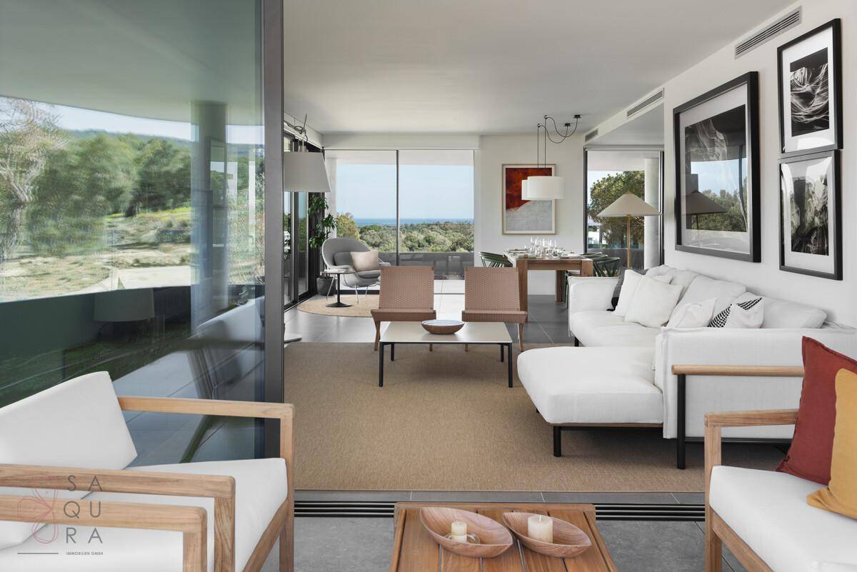 Großzügiges Wohnzimmer mit großen Fenstern, Meerblick und moderner Einrichtung.
