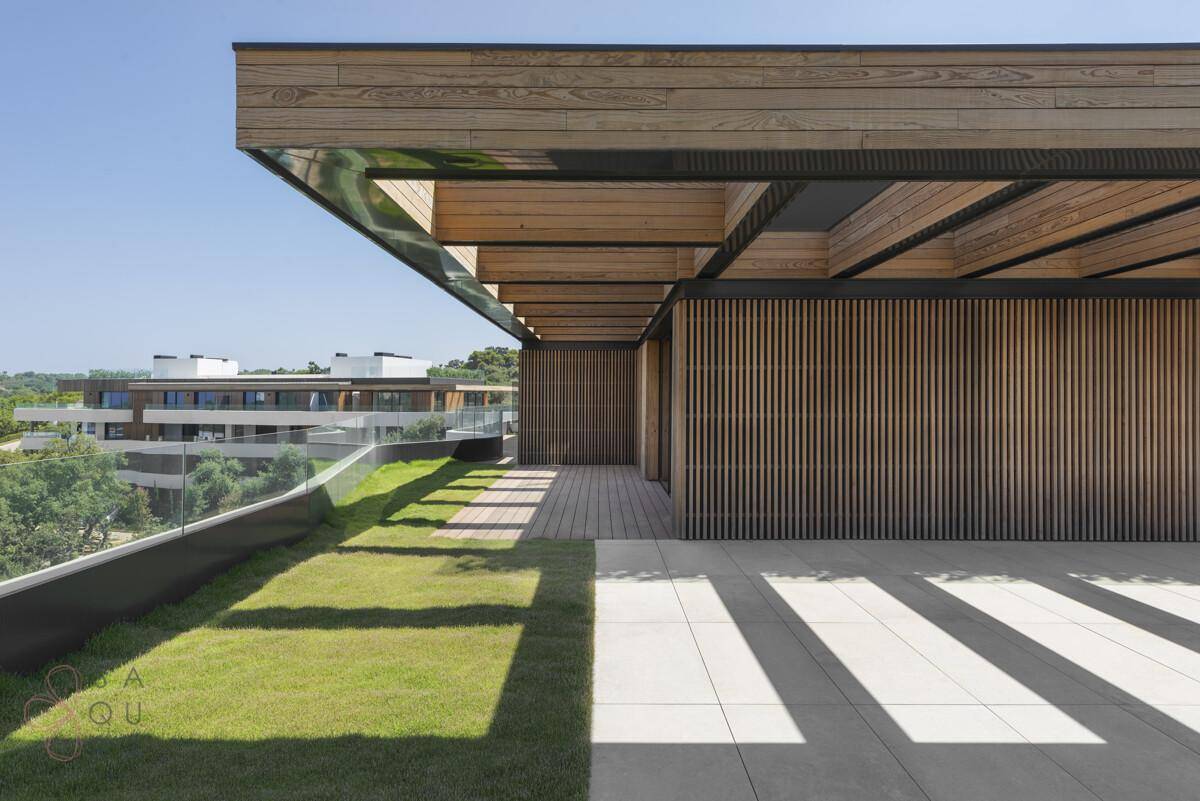 Geräumige Dachterrasse mit Rasenfläche, Fliesen und Holzverkleidung, ideal für Entspannung.
