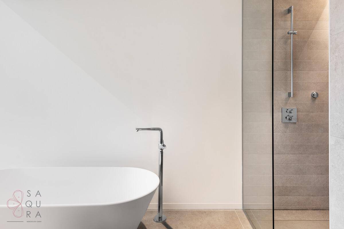 Modernes Badezimmer mit freistehender Badewanne, begehbarer Dusche und hellen Fliesen.
