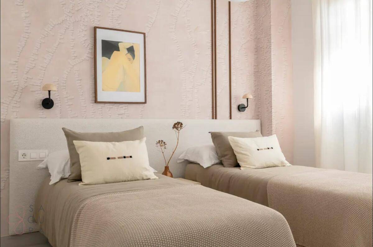 Schlafzimmer mit zwei Einzelbetten, heller Bettwäsche und dekorativer Wandgestaltung in Pastelltönen.