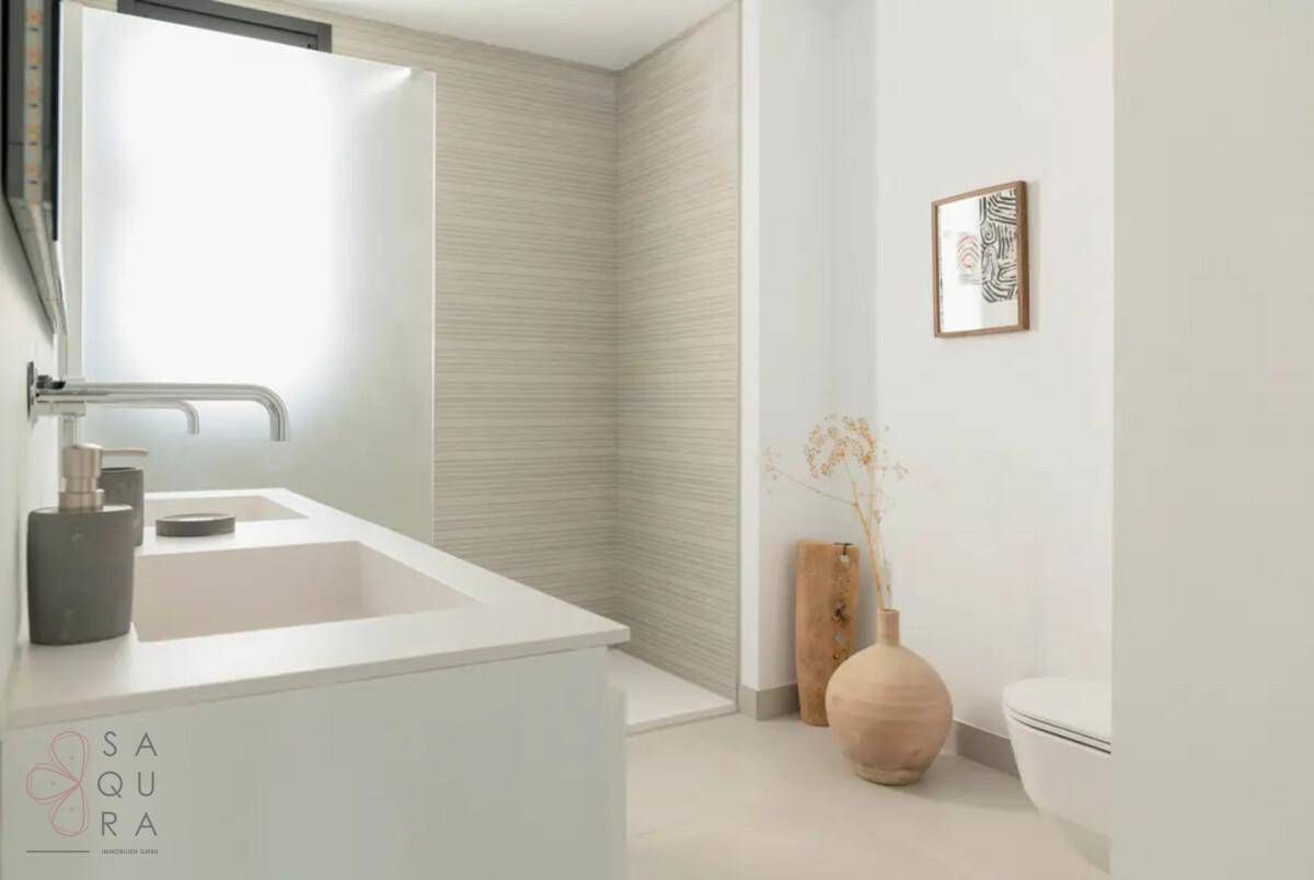 Modernes Badezimmer mit begehbarer Dusche, Doppelwaschbecken und wandhängendem WC in hellen Tönen.