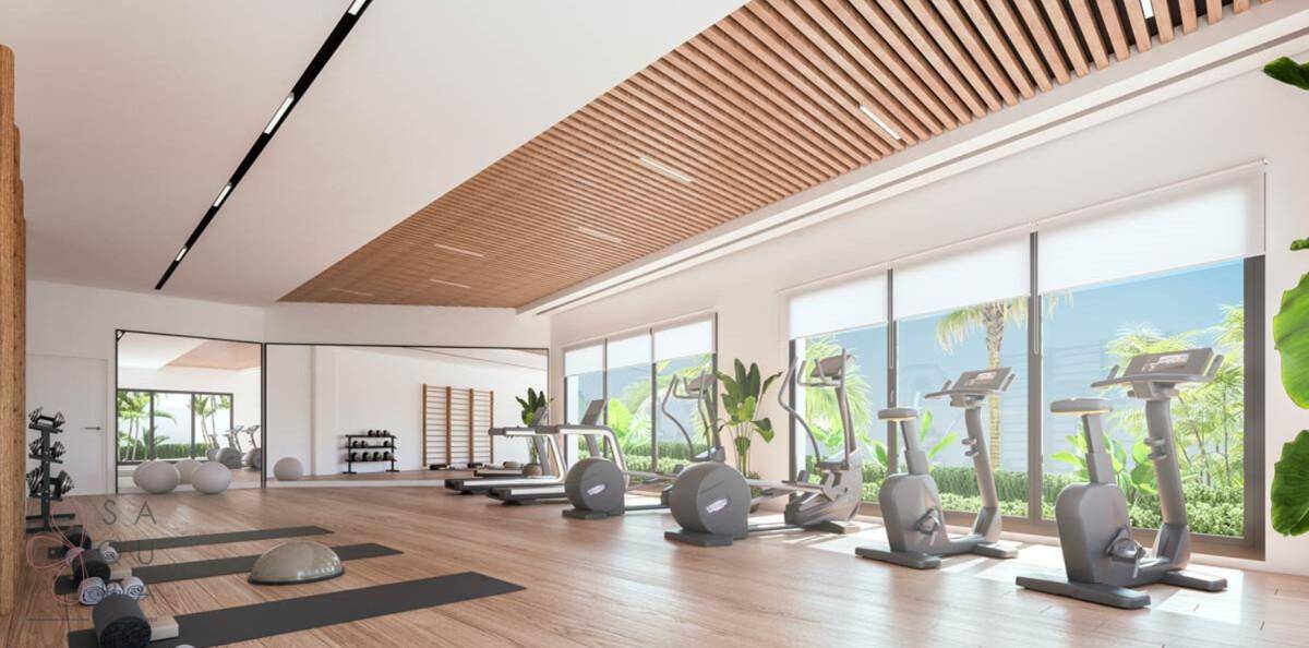 Heller Fitnessraum mit verschiedenen Trainingsgeräten, Holzakzenten und großen Fenstern.