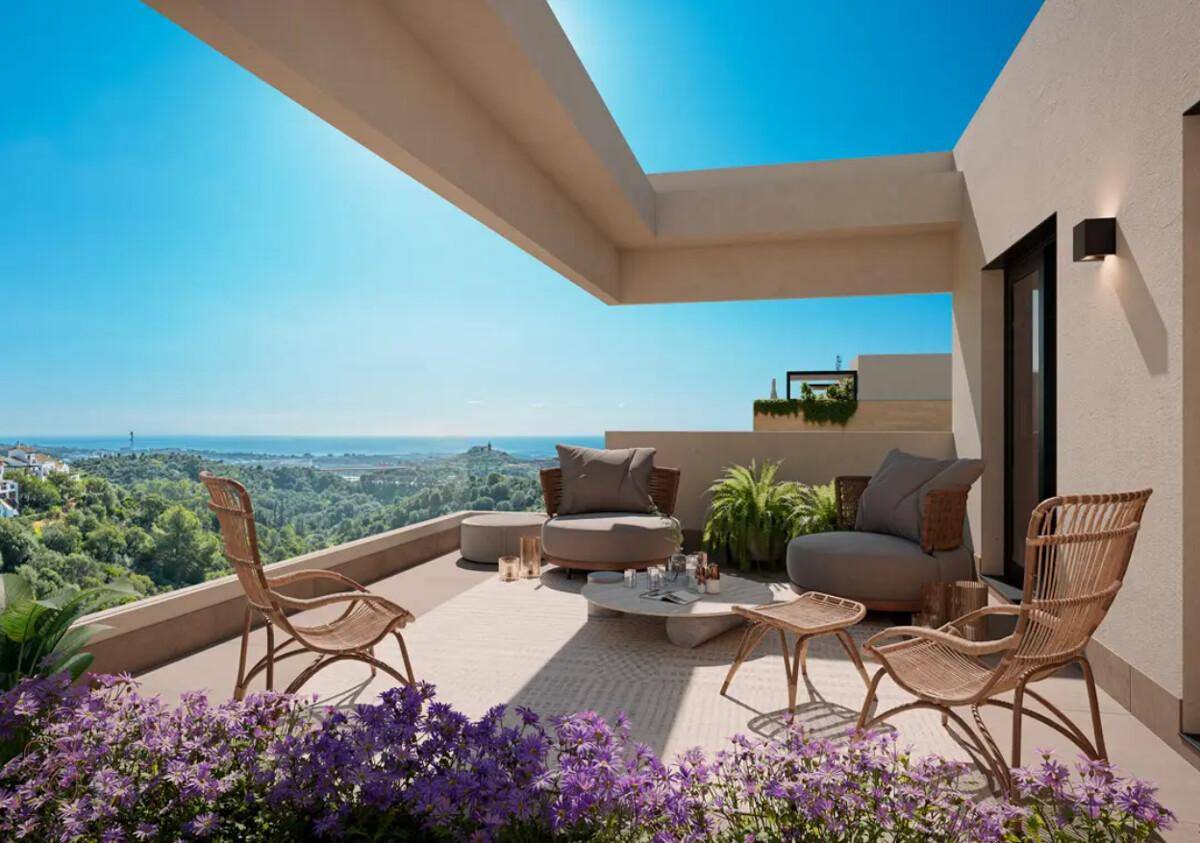Sonniger Balkon mit bequemen Loungemöbeln und weitem Blick auf das Meer und die grüne Landschaft.