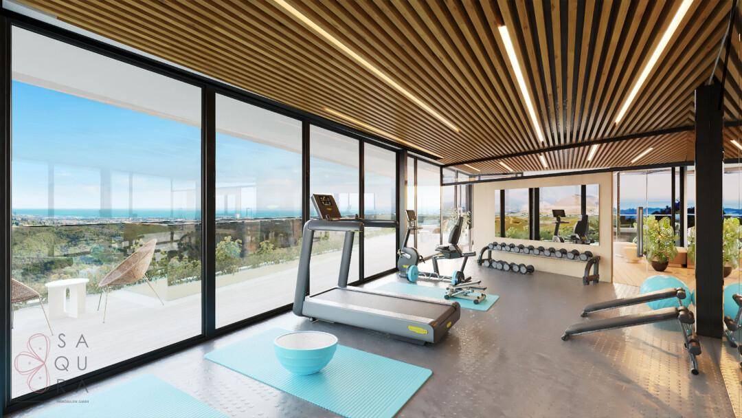 Moderner Fitnessraum mit verschiedenen Trainingsgeräten und großen Fenstern mit weitem Ausblick.