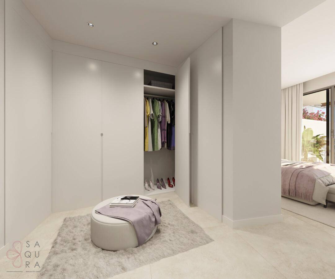 Heller begehbarer Kleiderschrank mit Einbauschränken und Blick in das angrenzende Schlafzimmer.