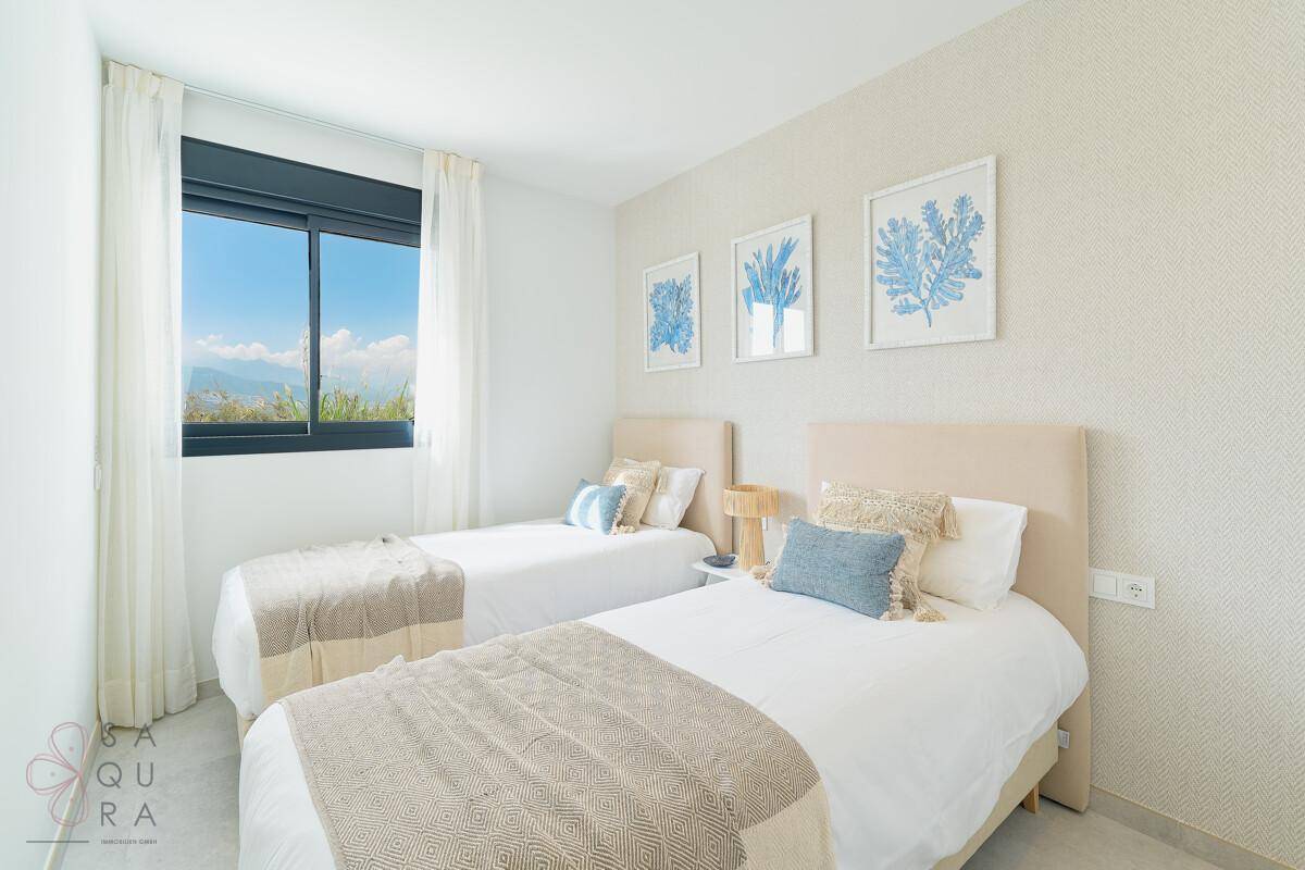 Helles Schlafzimmer mit zwei Einzelbetten und Blick auf die grüne Umgebung.