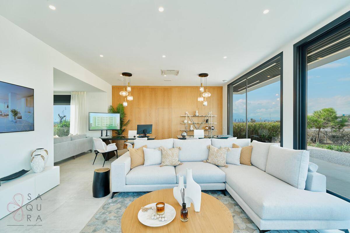 Helles, modernes Wohnzimmer mit großem Ecksofa, Holzwand und bodentiefen Fenstern.