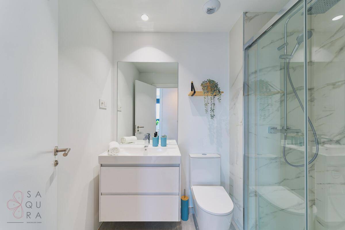 Modernes Badezimmer mit Duschkabine, Waschtischunterschrank und Wand-WC.