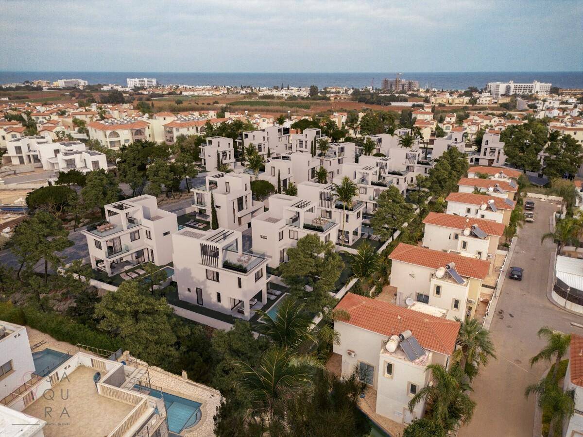 Weitläufige Luftaufnahme einer modernen Wohnanlage mit zahlreichen Villen, Gärten und Meerblick.