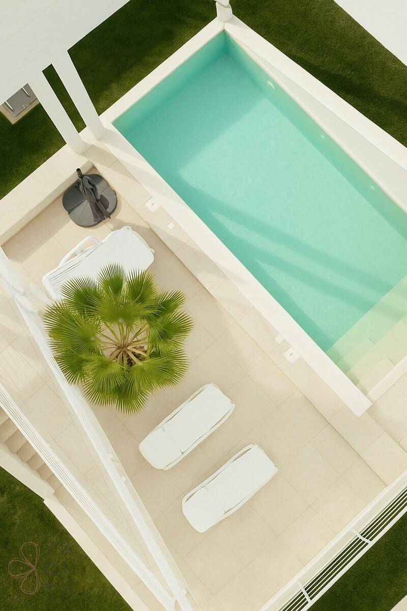 Türkisblauer Poolbereich mit Sonnenliegen und einer Palme, umgeben von hellem Fliesenboden.