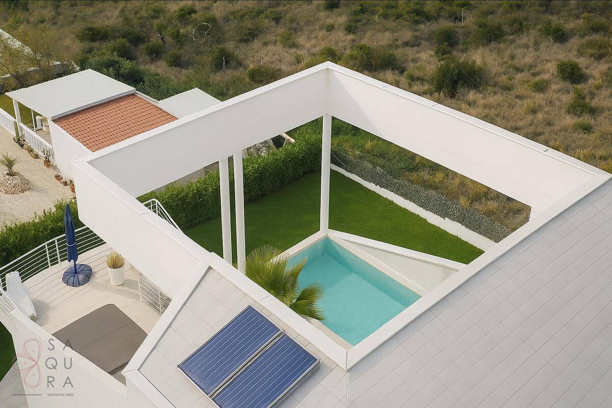 Dachansicht der modernen Villa mit integriertem Pool und Solarpaneelen auf dem Flachdach.