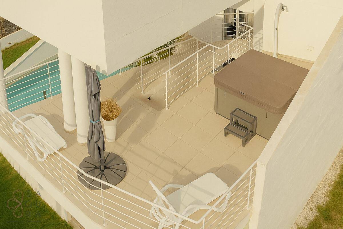 Geräumige Terrasse mit Whirlpool, Sonnenliegen und einem Sonnenschirm, ideal zum Entspannen.