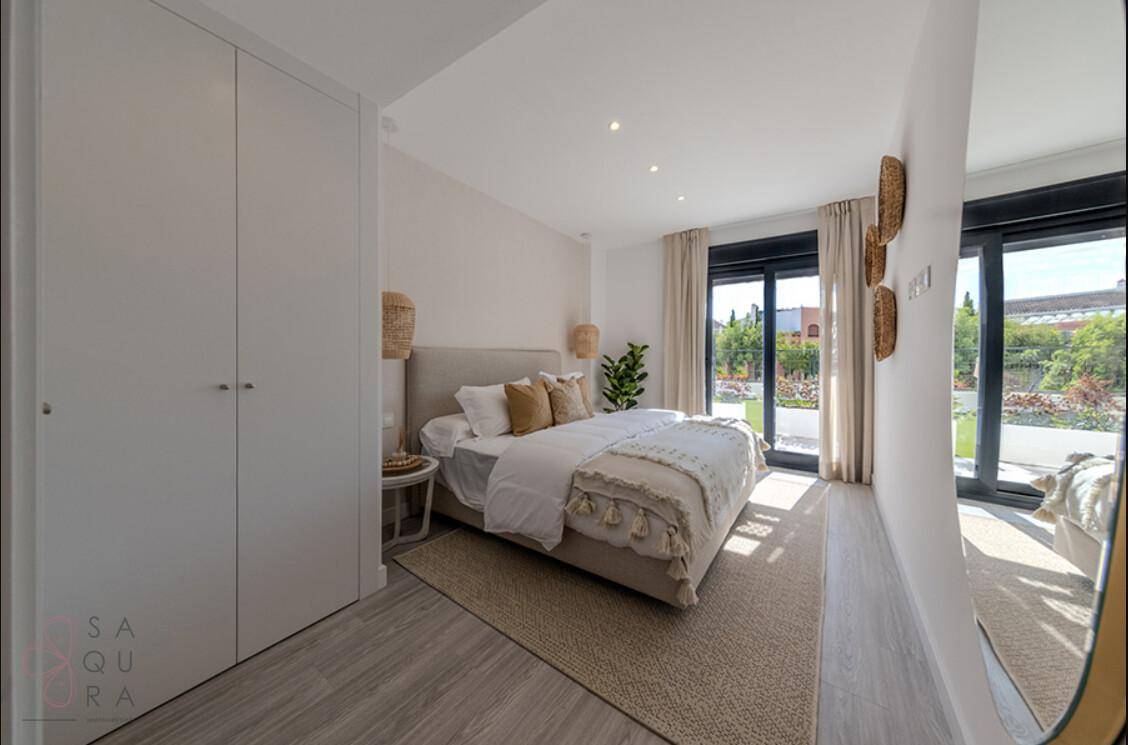 Helles Schlafzimmer mit großen Fenstern, Holzboden und integrierten Kleiderschränken.