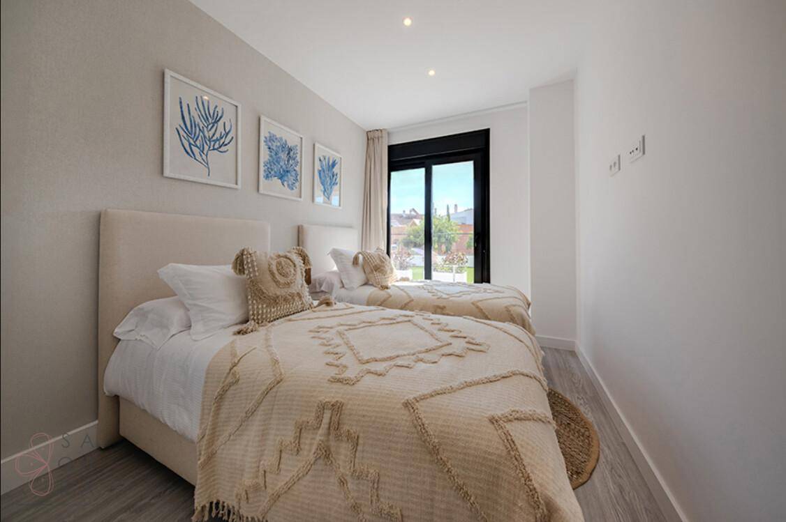 Helles Gästezimmer mit zwei Einzelbetten, Holzboden und modernen Wanddekorationen.