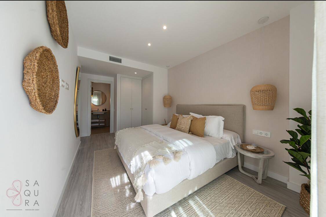 Gemütliches Schlafzimmer mit neutralen Farben, Holzboden und Zugang zum eigenen Badezimmer.