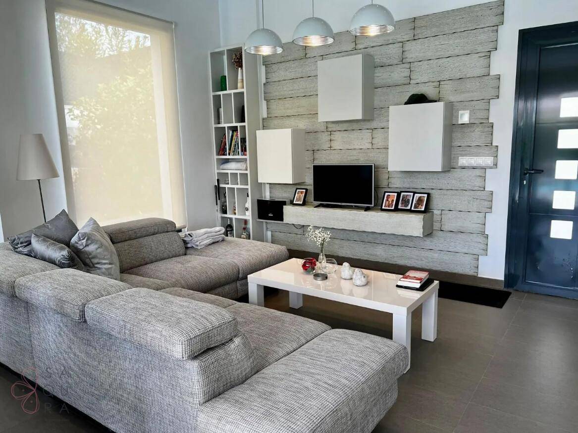 Helles Wohnzimmer mit großem Ecksofa und einer modern gestalteten TV-Wand.