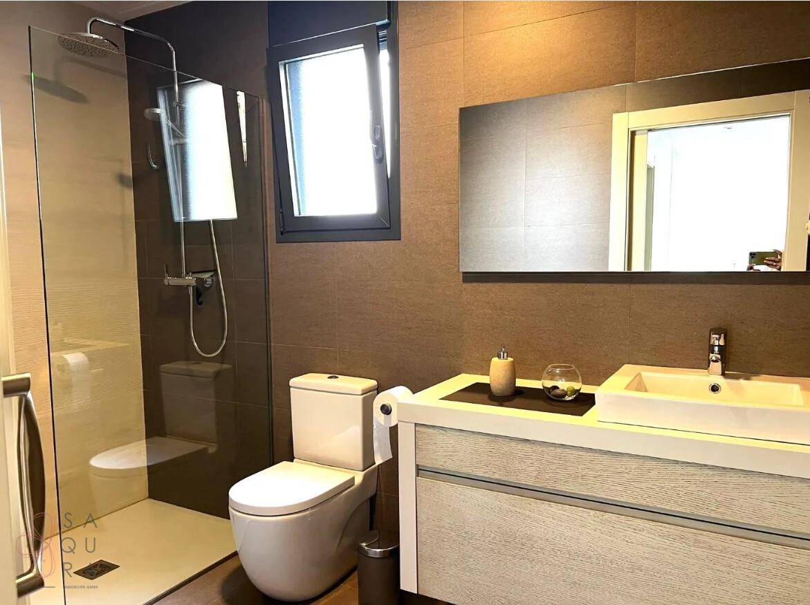 Modernes Badezimmer mit ebenerdiger Dusche, Waschtisch und Fenster.