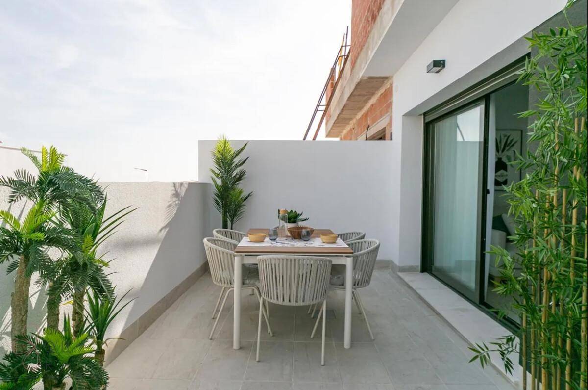 Terrasse mit Essbereich und Pflanzen, angrenzend an ein im Bau befindliches Gebäude.