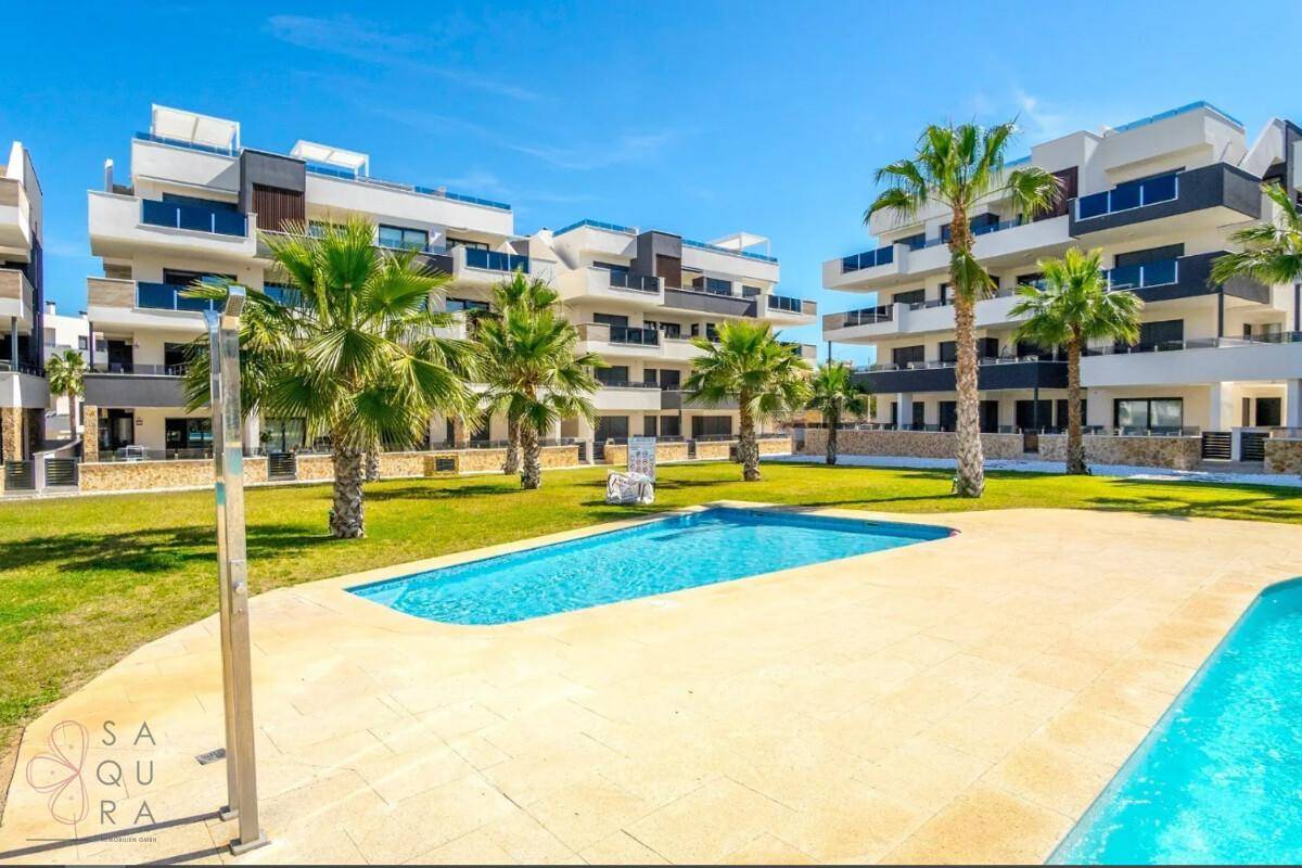 Moderner Apartmentkomplex mit großem Gemeinschaftspool und sonnigen Liegeflächen im Freien.