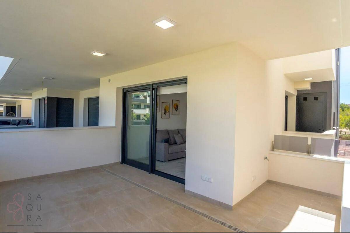 Heller Balkon mit Fliesenboden und Zugang zum Wohnbereich durch eine große Schiebetür.