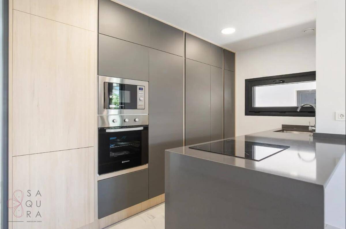 Elegante moderne Küche mit integrierten Geräten, Kochinsel und Fenster für natürliches Licht.