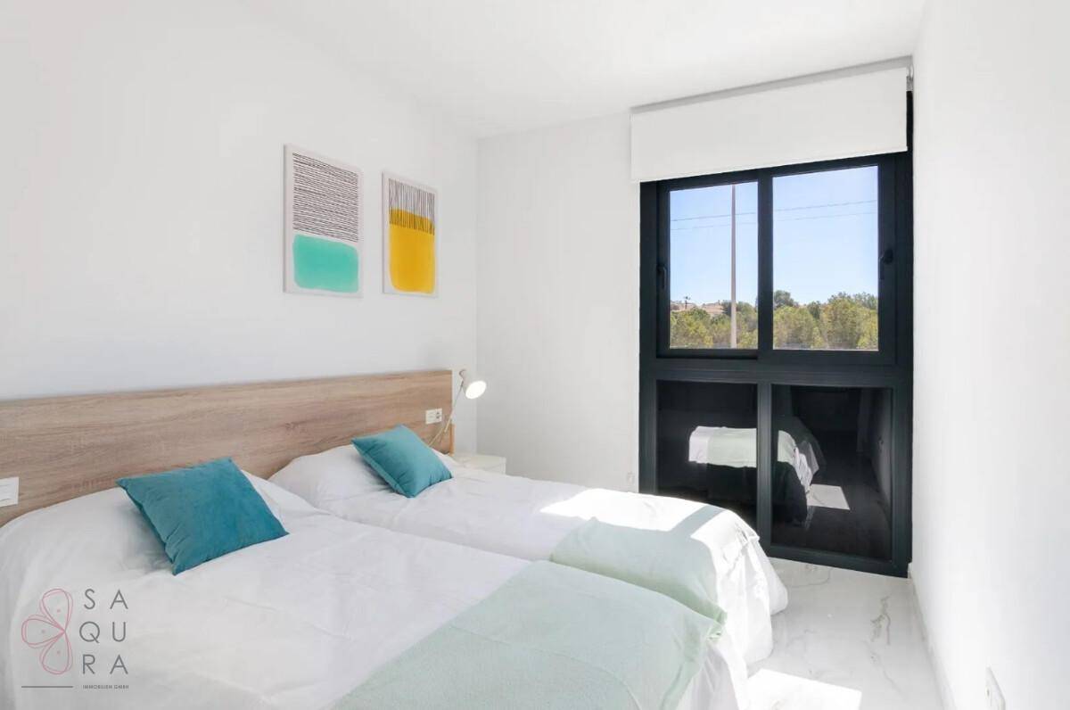 Helles Schlafzimmer mit zwei Einzelbetten, Einbauschrank und großem Fenster mit Ausblick.