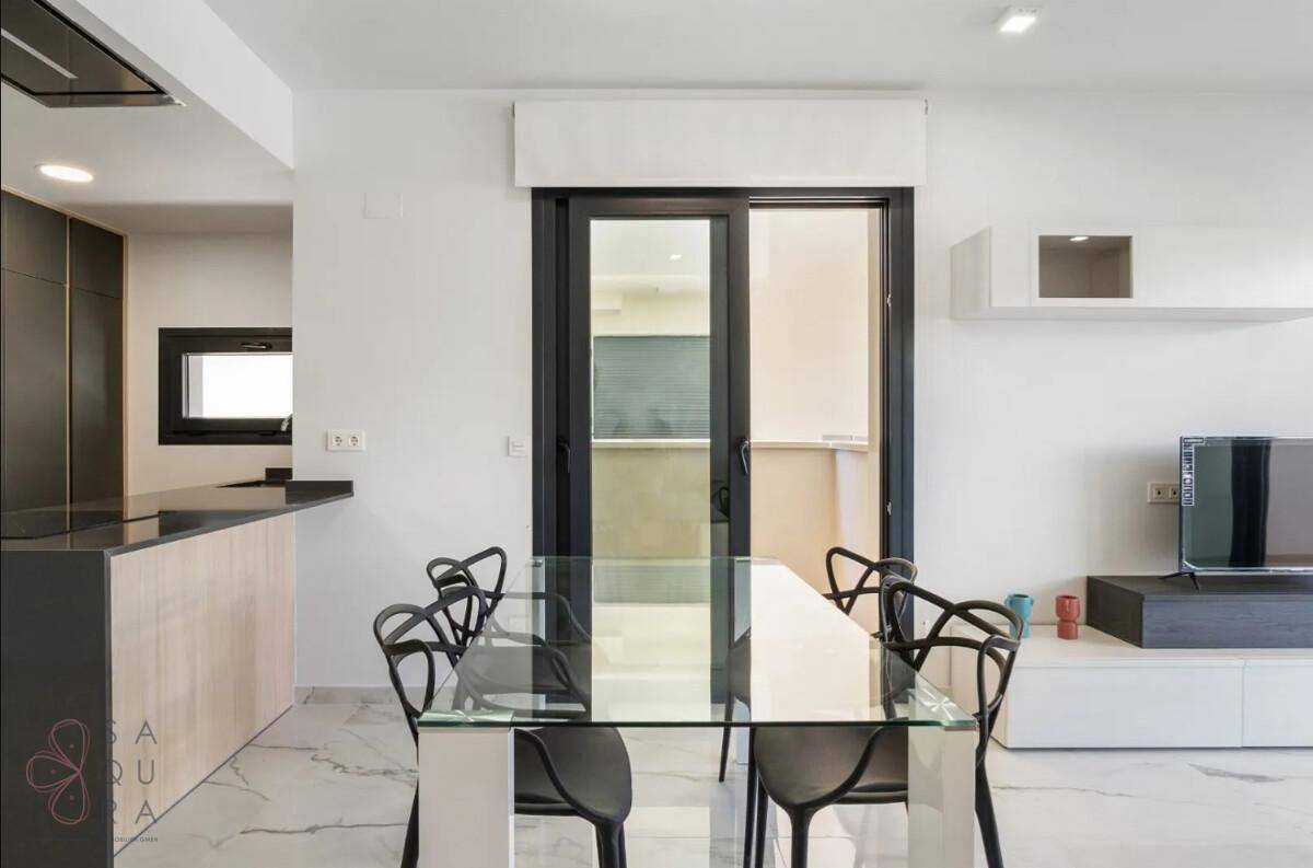 Essbereich mit Glastisch und modernen Stühlen, angrenzend an die offene Küche und Balkon.