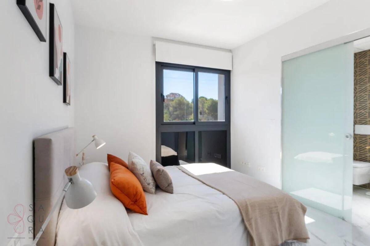 Helles Schlafzimmer mit Doppelbett, modernen Kunstwerken und Blick ins Grüne durch das Fenster.