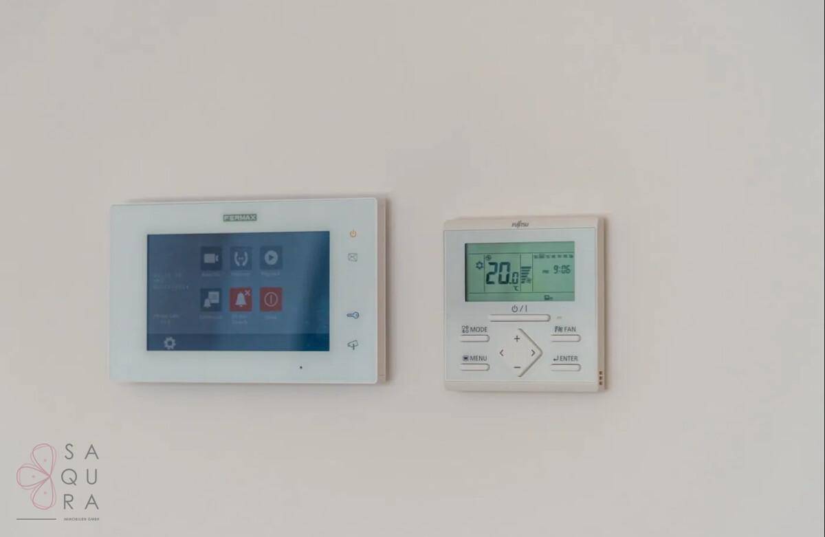 Wandmontierte Steuerungselemente für Klimaanlage und Gegensprechanlage in modernem Design.