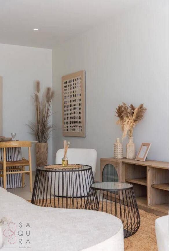 Detailansicht des Wohnbereichs mit stilvoller Dekoration, Rattan-Spiegel und modernen Beistelltischen.