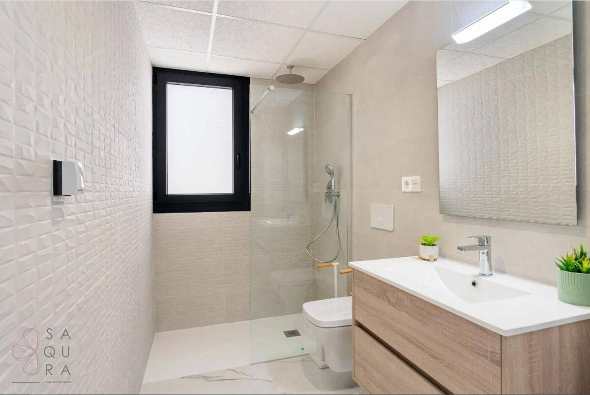 Helles Badezimmer mit begehbarer Dusche, Fenster und modernem Waschtischunterschrank.
