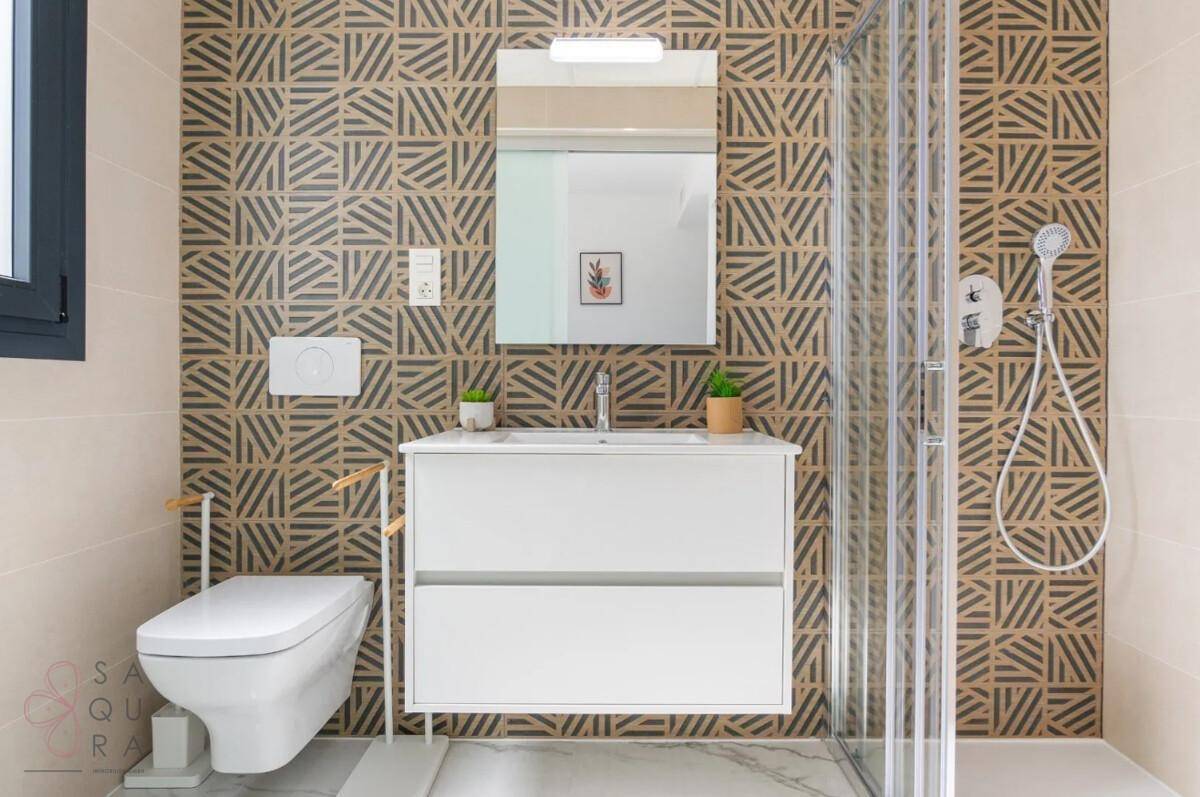Modernes Badezimmer mit Duschkabine, wandhängendem WC und auffälligen Fliesen an der Wand.