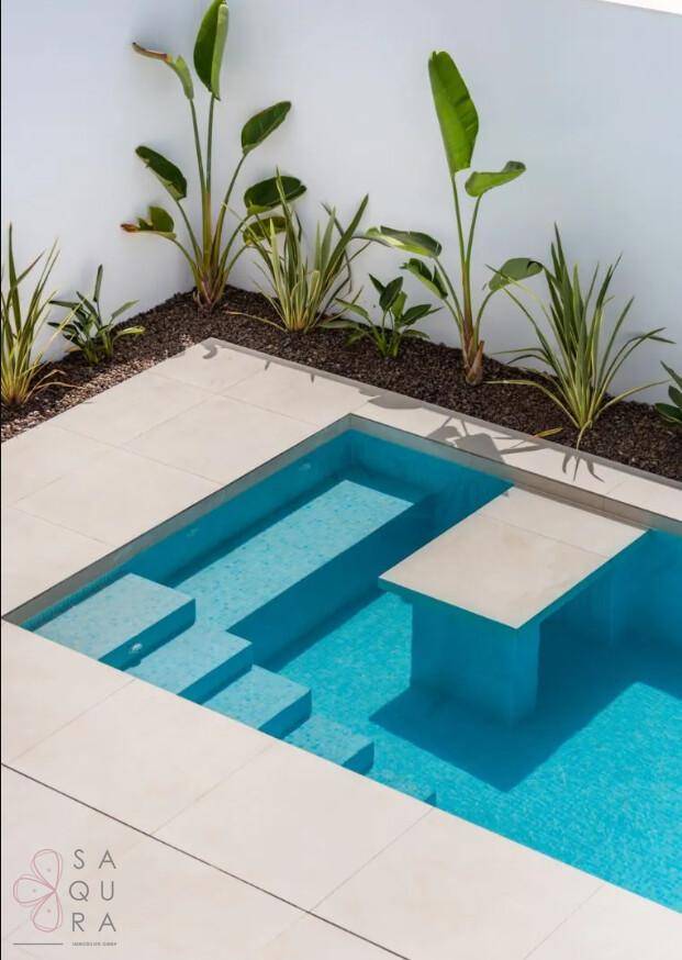 Detailansicht des modernen Pools mit integrierten Stufen und heller Fliesenumrandung.