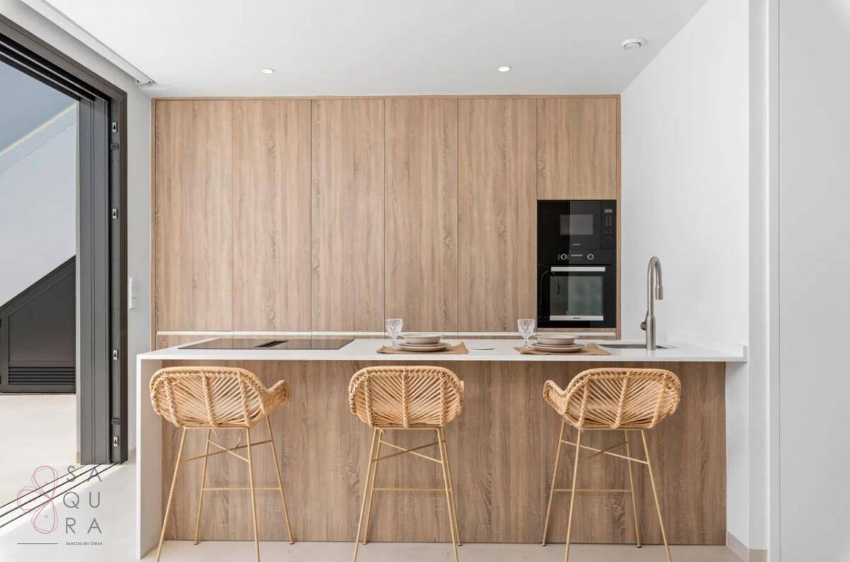 Moderne Küchenzeile mit Holzverkleidung, integrierten Geräten und einer praktischen Frühstücksbar.