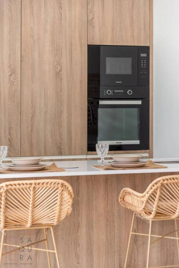 Hochwertige Miele-Einbaugeräte, Mikrowelle und Backofen, perfekt in die Holzküche integriert.