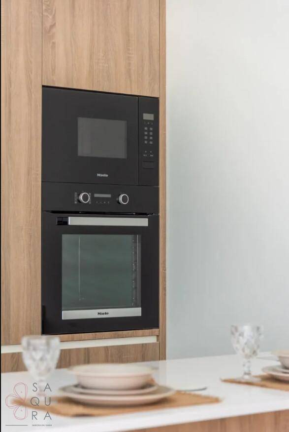 Integrierte Küchengeräte von Miele, bestehend aus Mikrowelle und Backofen, in Holzschrankwand.