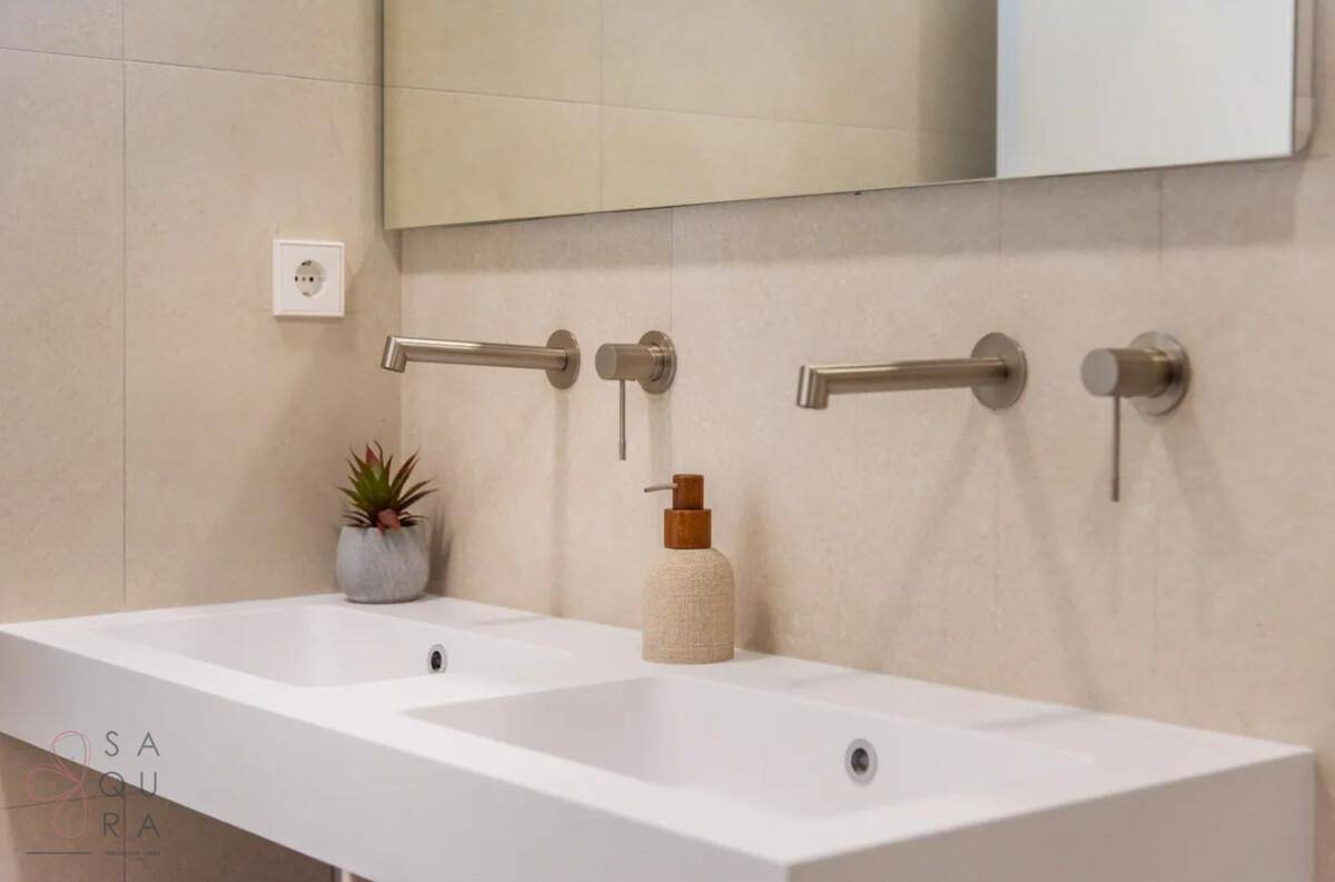 Modernes Doppelwaschbecken mit wandmontierten Armaturen und minimalistischem Design im Badezimmer.