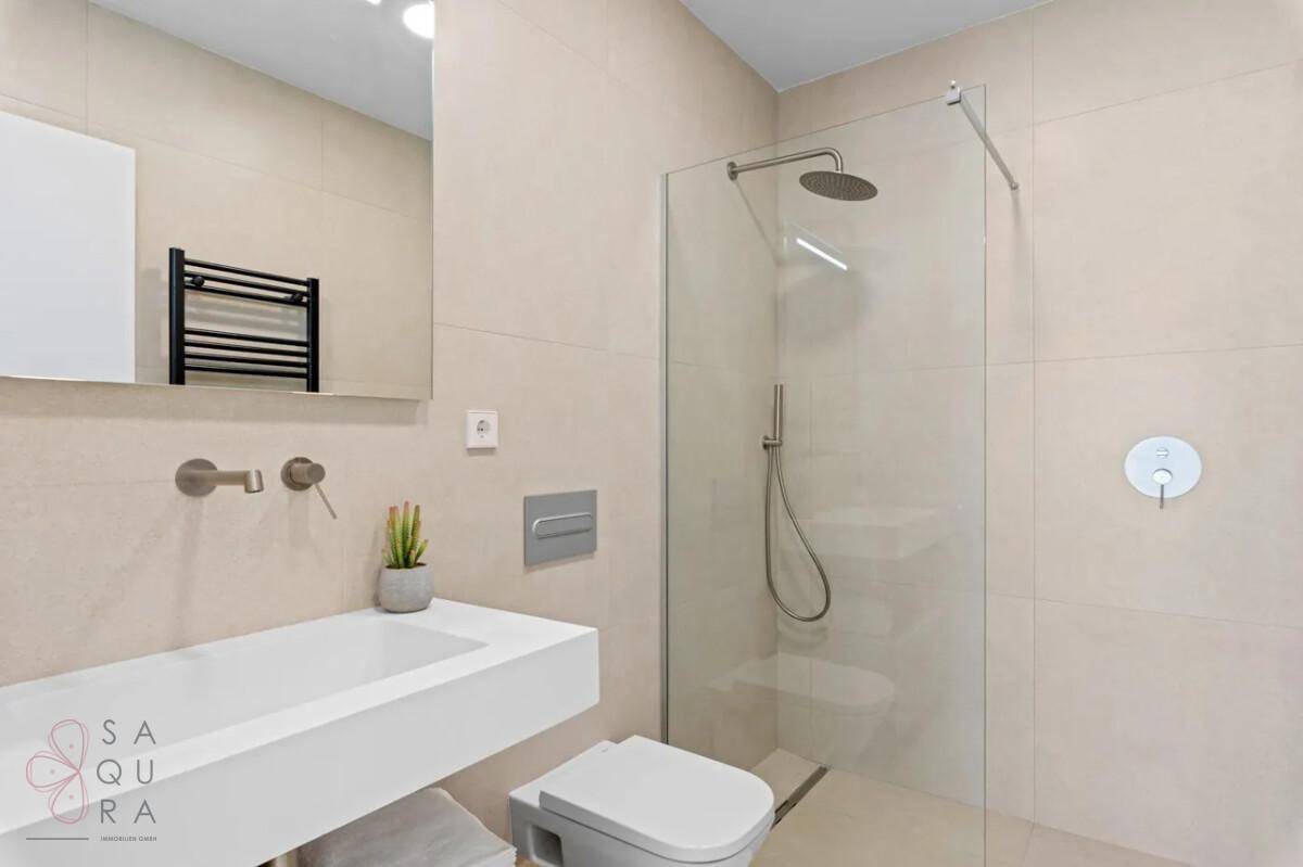 Modernes Badezimmer mit begehbarer Dusche, wandhängendem WC und elegantem Einzelwaschbecken.