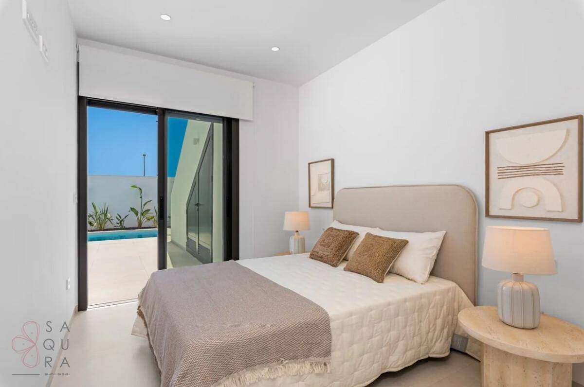Schlafzimmer mit Doppelbett und Schiebetür, die direkten Zugang zur Poolterrasse bietet.