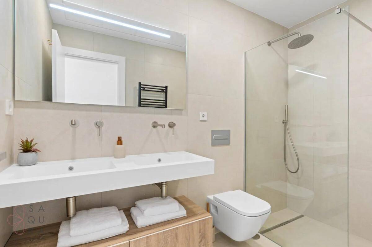 Helles Badezimmer mit Doppelwaschbecken, begehbarer Dusche und wandhängendem WC.