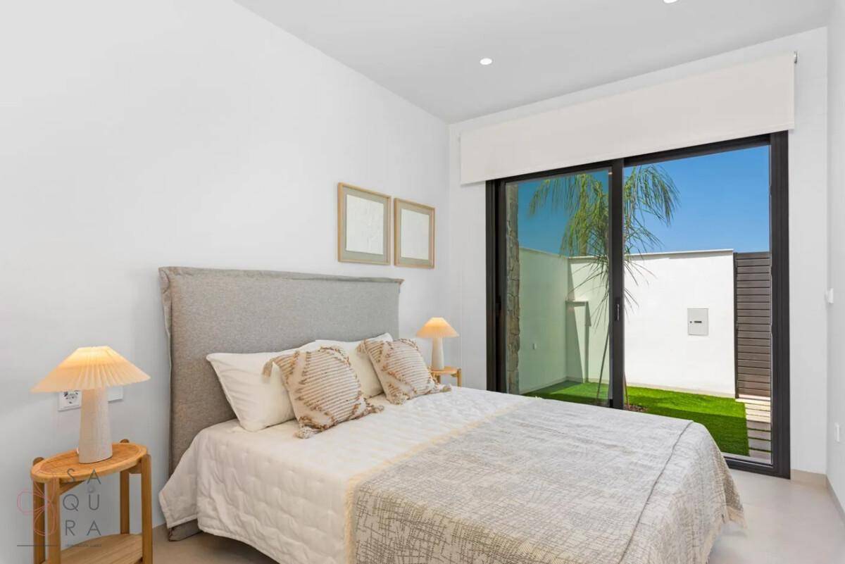 Schlafzimmer mit Doppelbett und großer Fensterfront, die den Blick auf den Außenbereich freigibt.