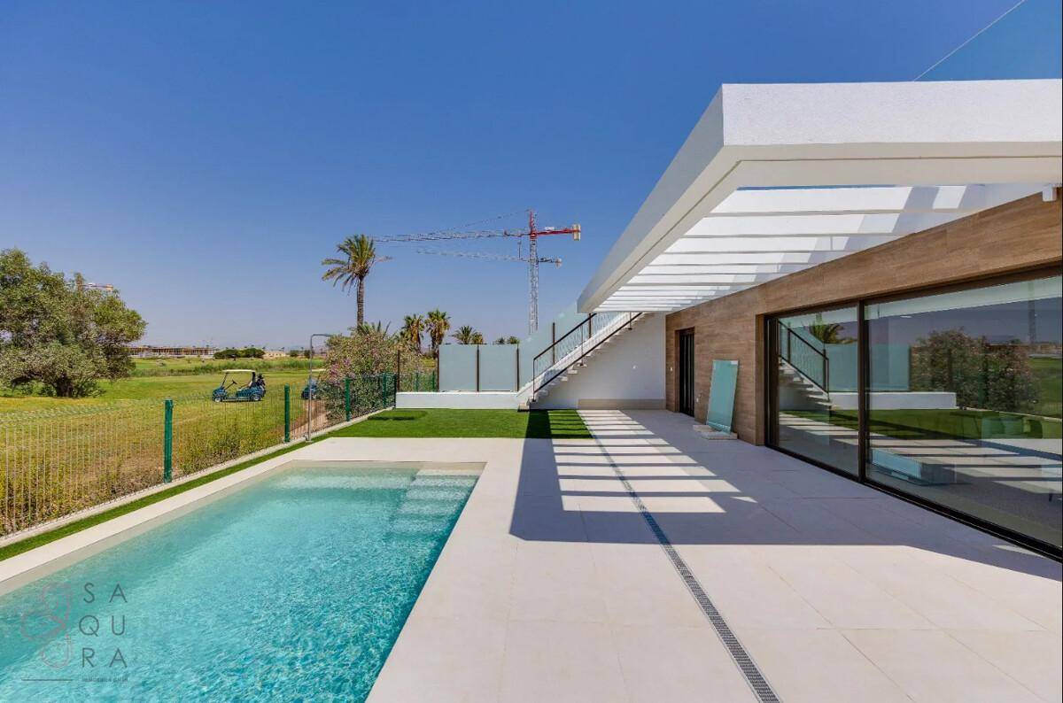 Außenbereich der modernen Villa mit Pool, Kunstrasen und Blick auf eine Golfanlage.