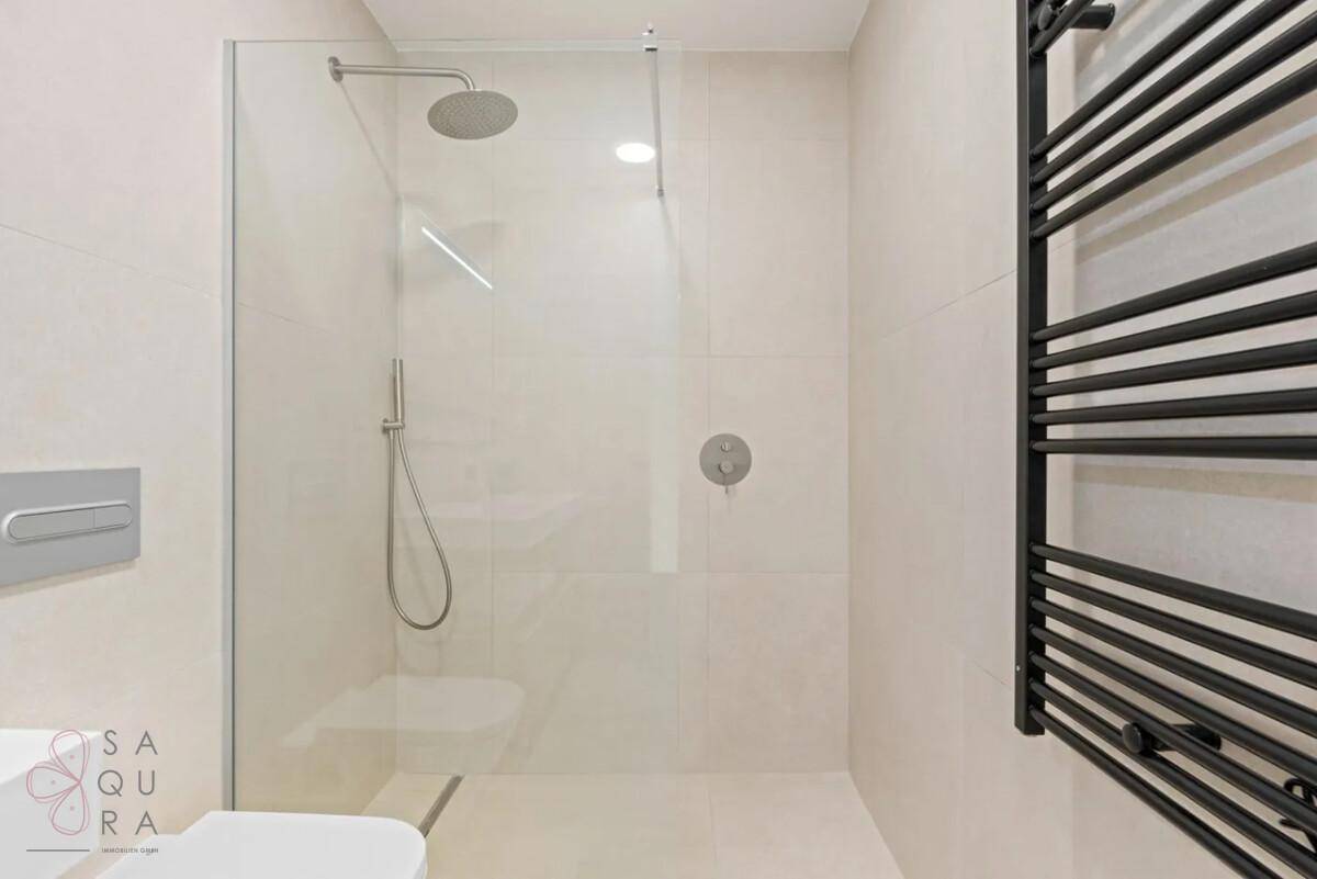 Geräumige, begehbare Dusche mit Regenduschkopf und moderner Glasabtrennung im Badezimmer.