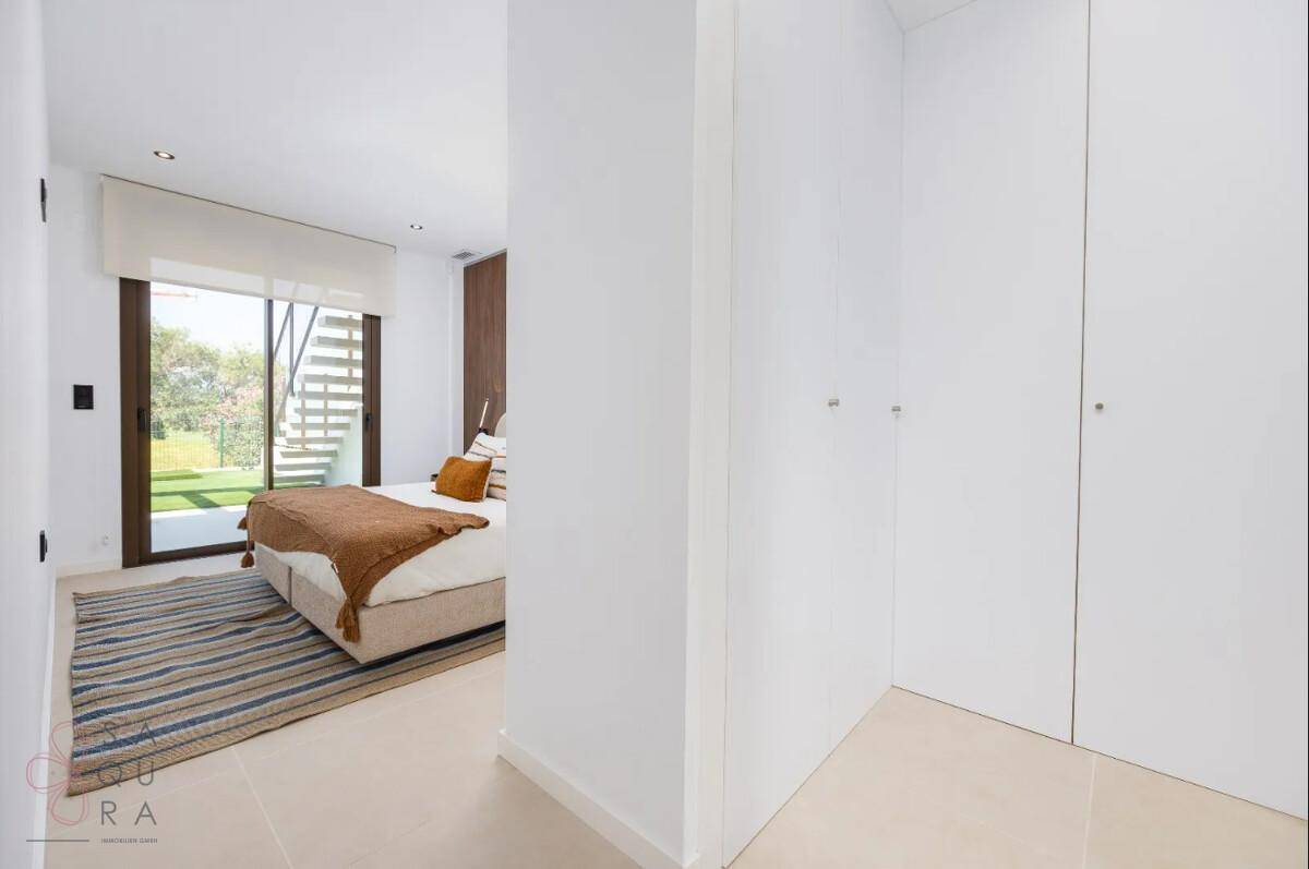 Heller Flur mit integrierten Kleiderschränken, der zu einem modernen Schlafzimmer führt.