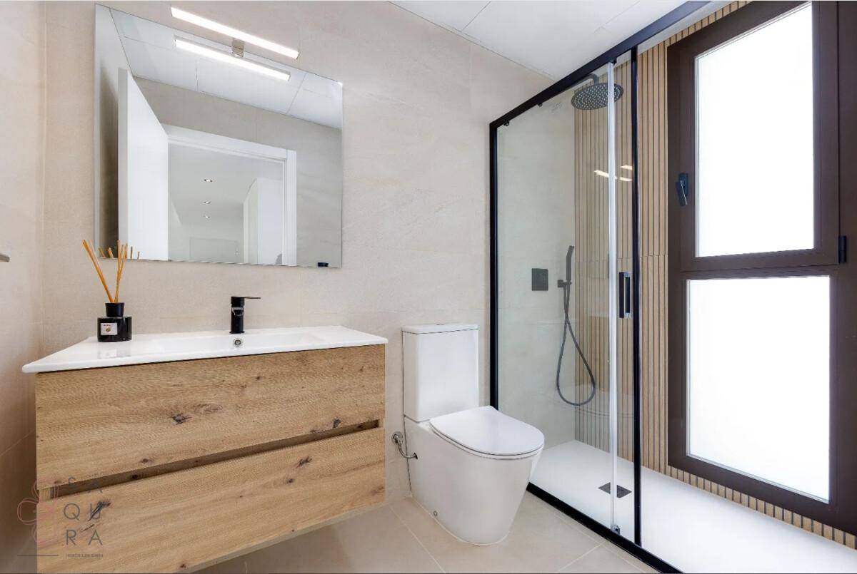 Modernes Badezimmer mit Duschkabine, Holzwaschtisch und Fenster für natürliche Belüftung.