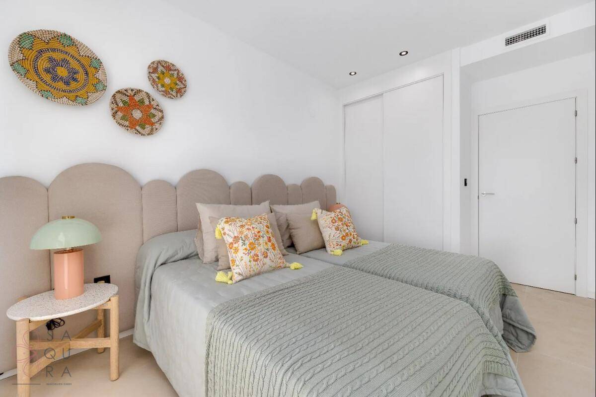 Freundliches Schlafzimmer mit zwei Einzelbetten, farbenfroher Dekoration und Einbauschränken.