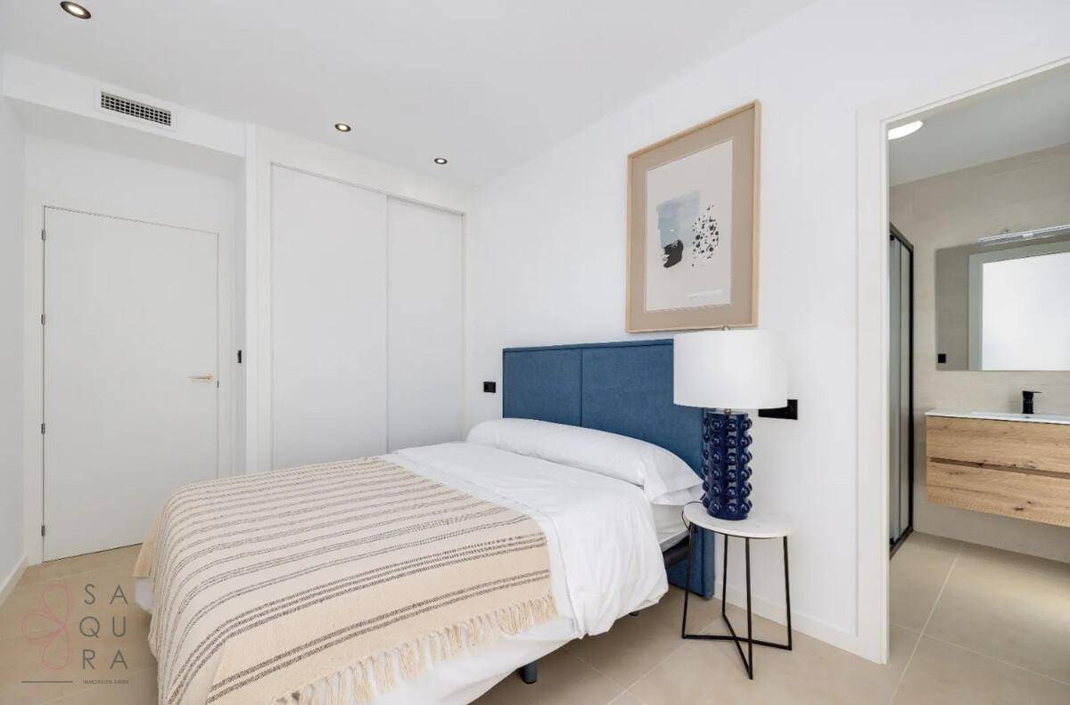 Komfortables Schlafzimmer mit blauem Kopfteil und direktem Zugang zu einem modernen Badezimmer.